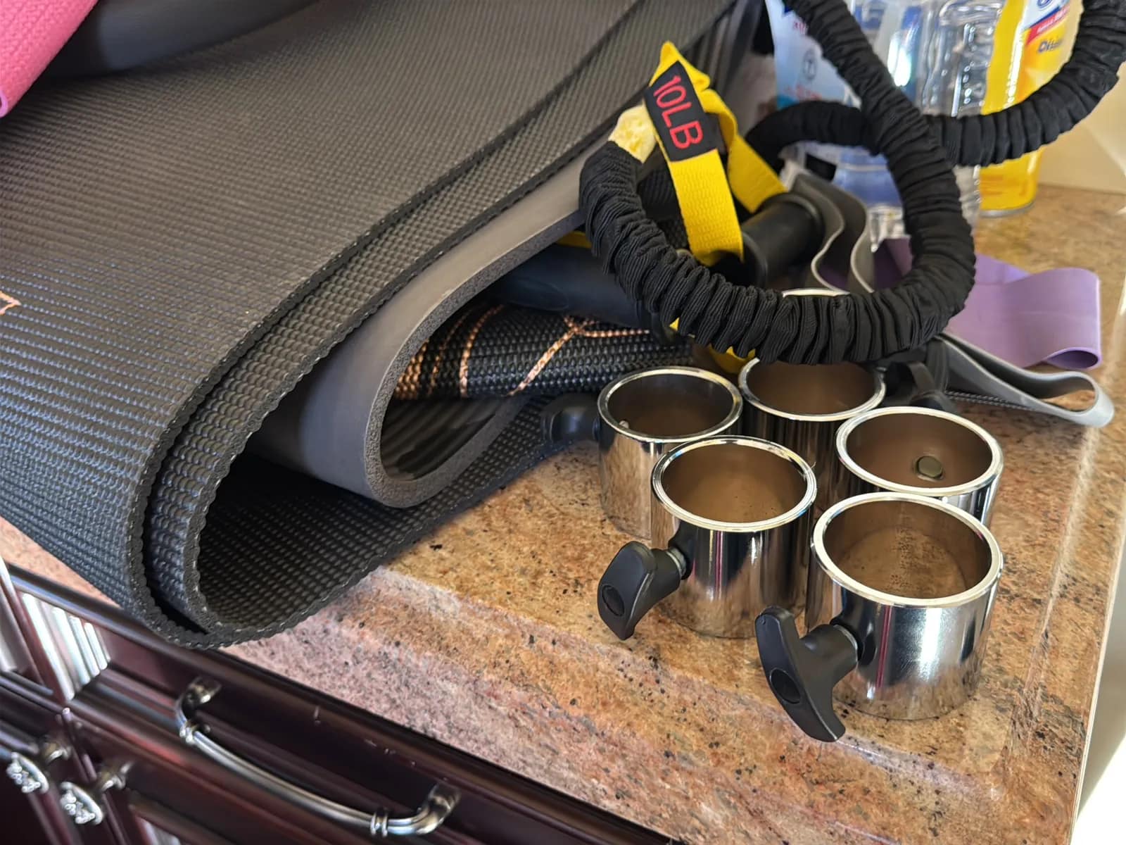 Contents Of Countertop: Kettlebells, Rubber Bands, Peloton Accessories, Yoga Mats, Pilates Equipment, And Machine Parts, photo 14 of 19