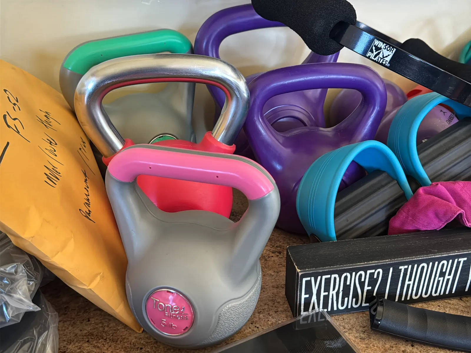 Contents Of Countertop: Kettlebells, Rubber Bands, Peloton Accessories, Yoga Mats, Pilates Equipment, And Machine Parts, photo 5 of 19
