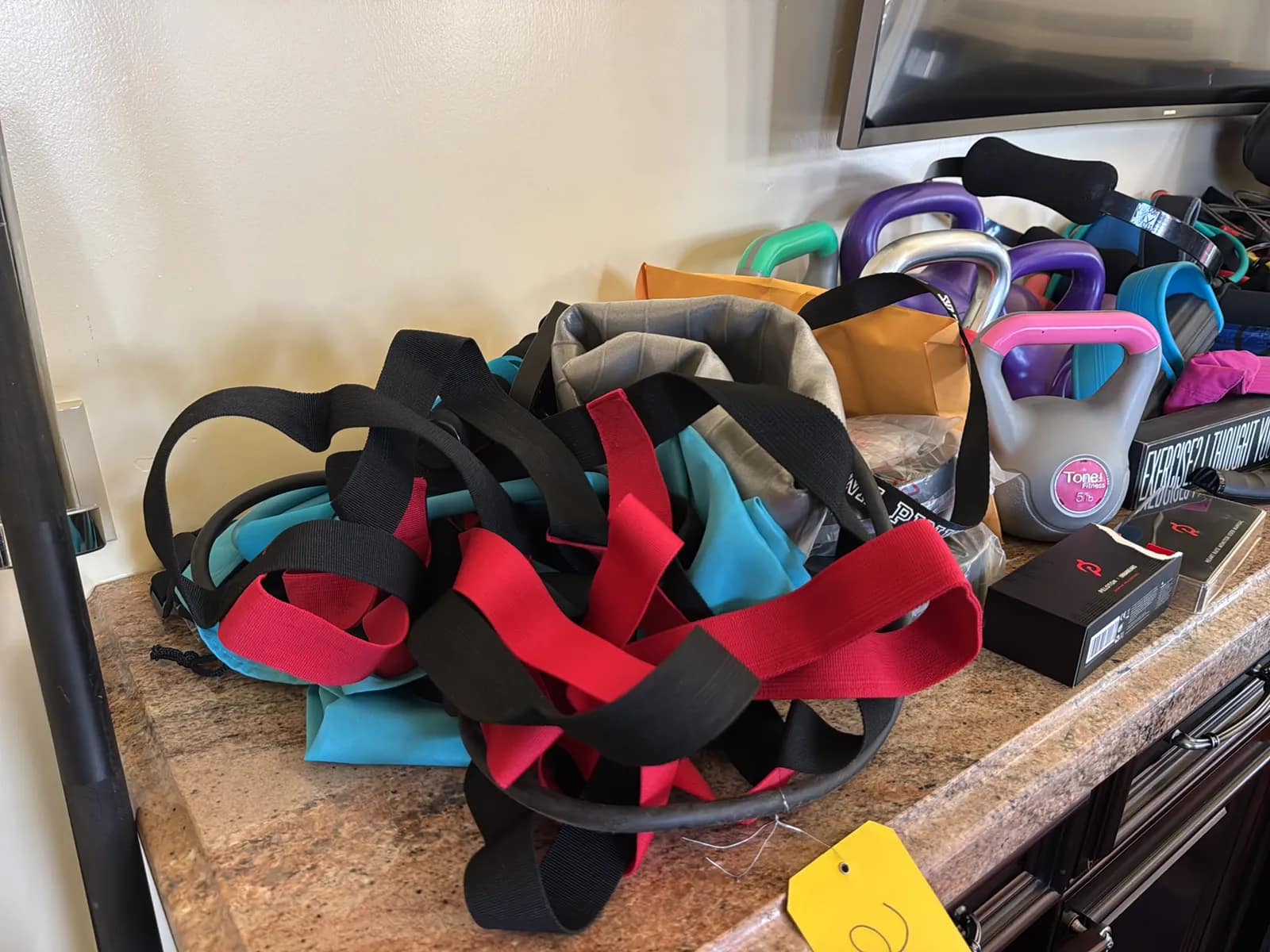 Contents Of Countertop: Kettlebells, Rubber Bands, Peloton Accessories, Yoga Mats, Pilates Equipment, And Machine Parts, photo 2 of 19
