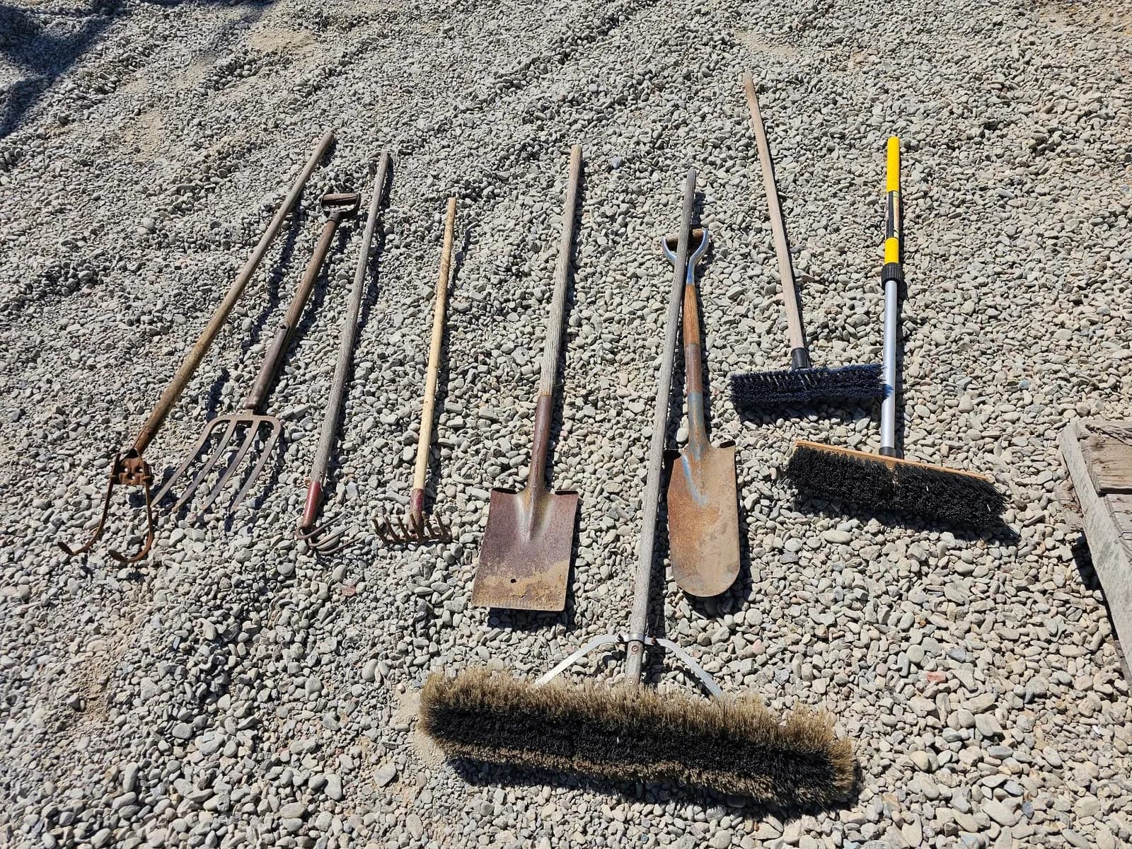 assorted-garden-tools-including-rakes-shovels-and-brooms-e7f03f